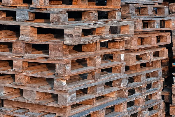 Many Old Used Wooden pallets is stack outdoors in the warehouse of cargo delivery enterprise.