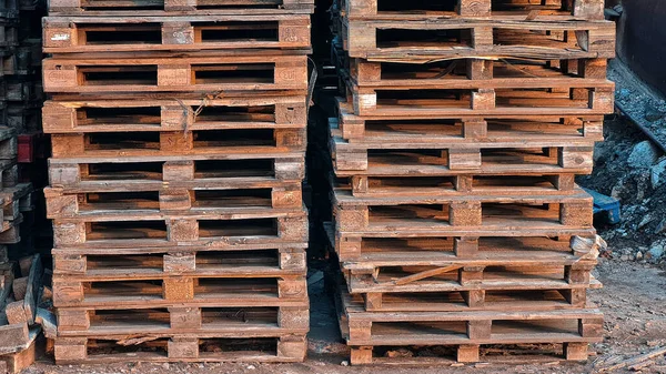 Many Old Used Wooden pallets is stack outdoors in the store of logistic enterprise.