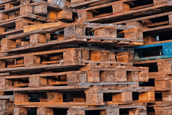 Many Old Used Wooden pallets is stack outdoors in the warehouse of cargo delivery enterprise.