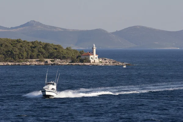 Моторная яхта и маяк — стоковое фото
