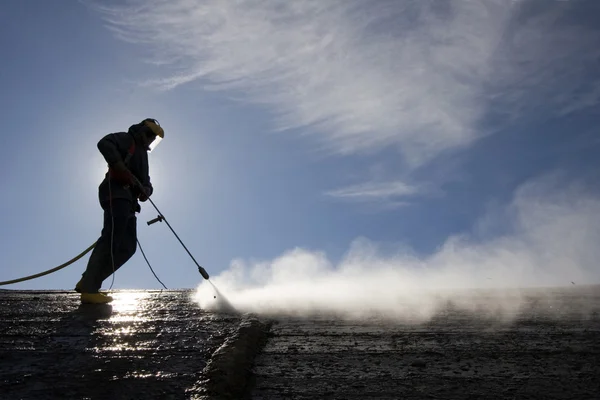 Worker on top of the factory hall cleans cement — Stock Photo, Image