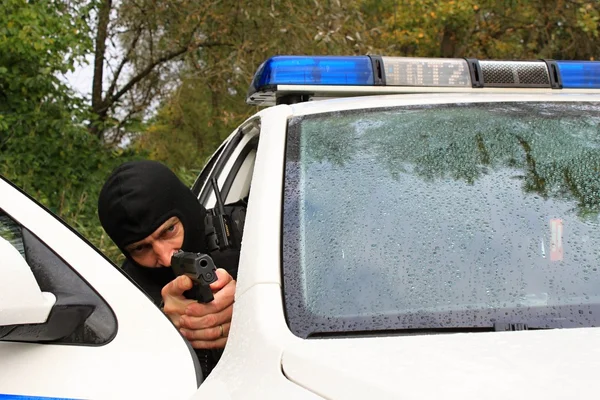 마스크를 쓴 경찰관 이 경찰차에서 총을 쏘다 — 스톡 사진