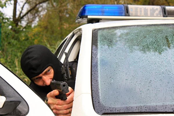 Maskerad polis skjuter från polisbil — Stockfoto