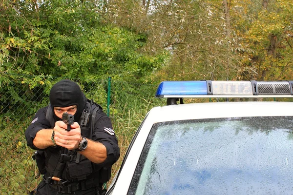 Maskovaný policista střílí z policejního auta — Stock fotografie