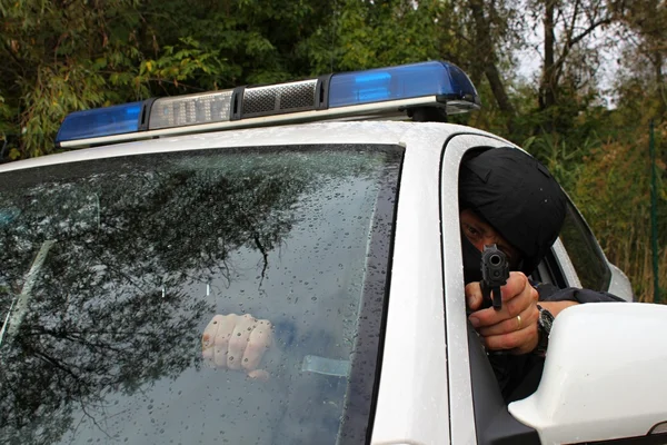 Masked policeman shoots from police car — Stock Photo, Image