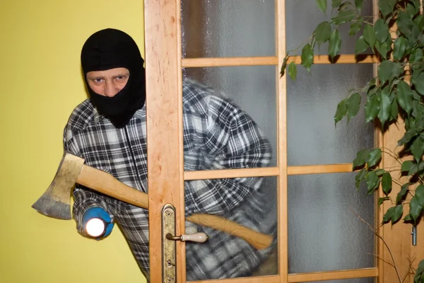 Ladrón en máscara irrumpiendo en una casa a través de la puerta, con pistola —  Fotos de Stock