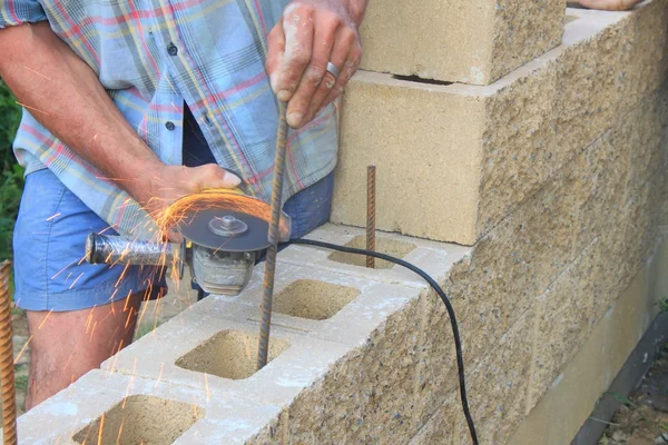 Pedreiro constrói uma parede, vergalhões moedor de ângulo de corte — Fotografia de Stock