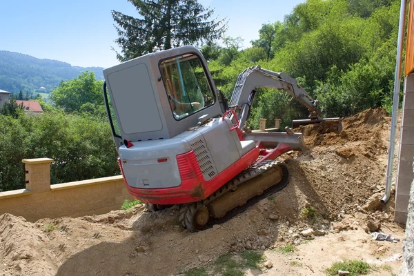 A small excavator provides garden at the house — Stock Photo, Image