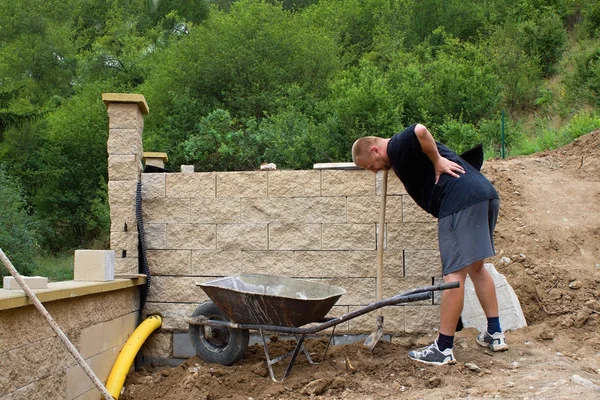 Back pain, bricklayer builds a wall — Stock Photo, Image