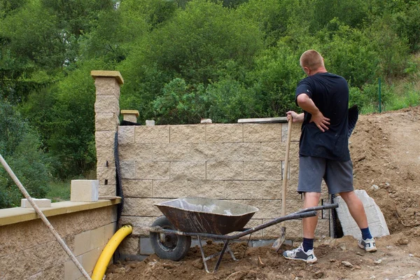 Боль в спине, каменщик строит стену — стоковое фото