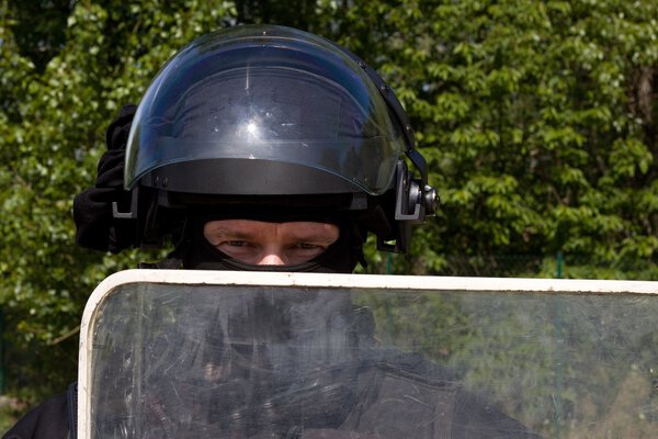 офицер полиции в защитном шлеме и козырьке, подготовка к демонстрации
