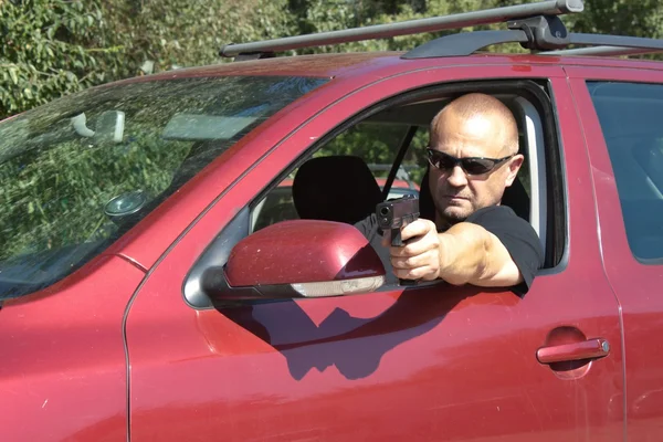 Assassin shooting from a moving car, aggressive driver — Stock Photo, Image