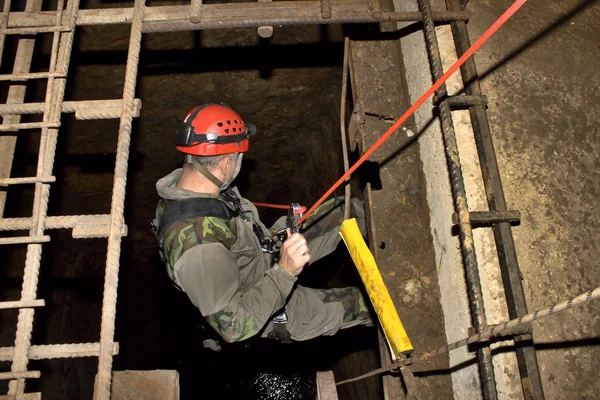 Police rescue worker runs the rope into the flooded old mine