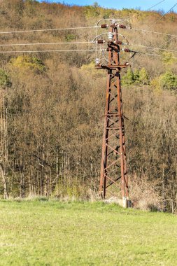 Eski paslı elektrik kaynağı. Yüksek voltajlı elektrik hattı. Elektrik direği ve arka planda kablolar. Elektrik kablolarıyla paslı demir elektrik direği
