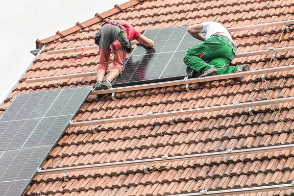 Man installing new solar panels on the roof of a private house. Renewable energy concept. Iinstallation of photovoltaics. Energy saving.