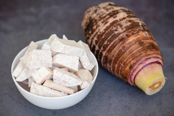 Taro root with slice cubes on bowl and dark background, Fresh raw organic taro root ready to cook