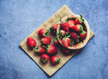 Taze çilek çuvalda, kırmızı olgun çilek arka planda, üst tarafta.