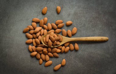 Masadaki koyu arkaplanda badem, kavrulmuş badem, doğal protein ve atıştırmalıklar. 