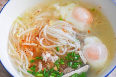 Çorba kasesi, domuz etli şehriye, Vietnam usulü domuz eti haşlanmış yumurta ve fasulye filizli sebze filizli soğan ahşap masada çorba kasesi, Tayland yemeği.