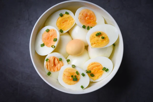 Eggs breakfast, fresh eggs menu food boiled eggs in a bowl decorated with leaves chopped fresh green onions on dark background, cut in half egg yolks ingredients for cooking healthy eating concept