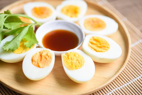 Eggs breakfast, fresh eggs menu food boiled eggs in a wooden plate decorated with leaves green celery and fish sauce on wooden background, cut in half egg yolks for cooking healthy eating