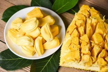 Tahta arka planda yaprak ile beyaz tabakta kaya meyvesi, olgunlaşmış meyveli tropikal meyve.