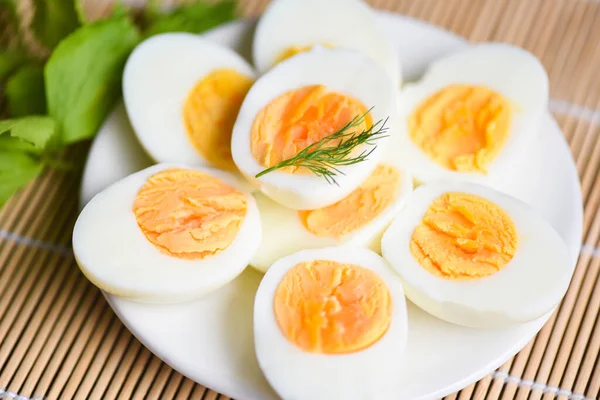 Eggs breakfast, fresh eggs menu food boiled eggs in a white plate decorated with leaves green dill background, cut in half egg yolks for cooking healthy eating