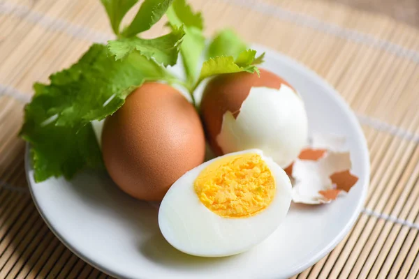 卵の朝食 新鮮な皮をむいた卵メニューの食べ物木製の背景に緑のセロリで飾られた白いプレート上のゆで卵と卵殻 卵料理健康的な食事のコンセプト — ストック写真