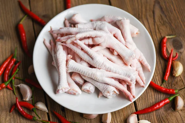 chicken feet on white plate with herbs and spices chili garlic, Fresh raw chicken feet for cooked food soup on the wooden table kitchen background