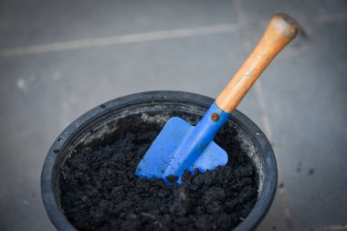 Ekmek için siyah tencerede kürek, saksıda bitki ya da çiçek yetiştirmek için toprak hazırlamak.