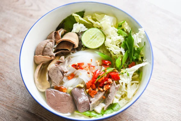 Thai rice vermicelli noodle with clear soup and fresh vegetable set with lemon sprouts bean pepper chili sauce Thai traditional menu food, Noodle soup bowl pork blood pudding and pork offal