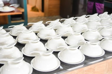 Masada boş fincan ve kaşık, beyaz kase çorba servisi için hazır.