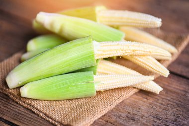 Yatakta bebek mısırı, sağlıklı yemek pişirmek için taze taze taze mısır, ahşap arka planda çiğ organik mısır..