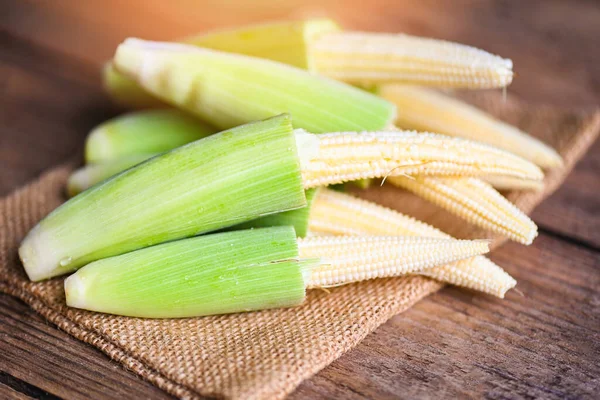 Yatakta bebek mısırı, sağlıklı yemek pişirmek için taze taze taze mısır, ahşap arka planda çiğ organik mısır..