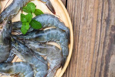 Ahşap tabakta çiğ karides, nane yaprağı ve ahşap tahta zemin yemek pişirmek için, taze karides ya da karides kaplamak için, deniz ürünleri kabukluları 