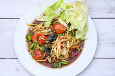 Tayland yemeği papaya salatası lahana bahçeli uzun fasulye beyaz tabak, papaya salatası yengeç ve mayalanmış balık.