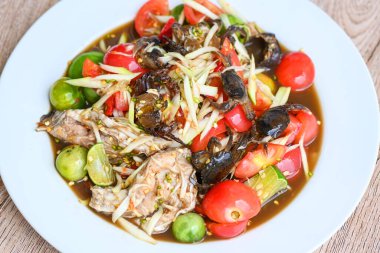 Beyaz tabakta yengeç, Tayland yemeği papaya salatası baharatlı ve mayalanmış balık.  