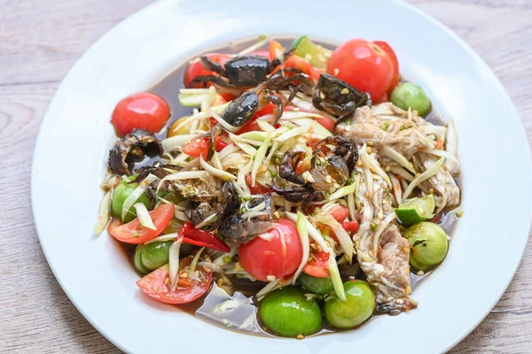 Beyaz tabakta yengeç, Tayland yemeği papaya salatası baharatlı ve mayalanmış balık.  