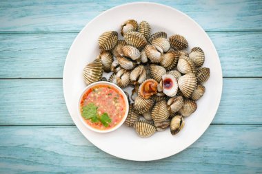 Taze çiğ kabuklu deniz ürünleri restoranda deniz ürünleri, arka planda deniz ürünleri sosu ile beyaz tabakta midyeler.