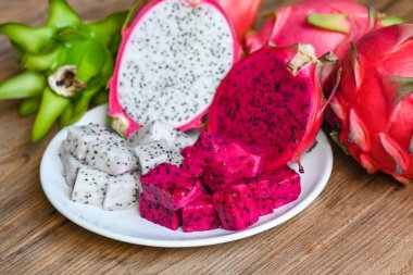 ejderha meyvesi dilimi ve yarısı pitahaya arka planlı beyaz tabakta, taze beyaz ve kırmızı mor ejderha meyvesi Asya Tayland ve sağlıklı meyve kavramında tropikal