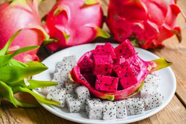 Asya Tayland ve sağlıklı meyve kavramında tropikal taze beyaz ve kırmızı ejderha meyvesi, pitahaya arka planında beyaz tabakta ejderha meyvesi dilimi