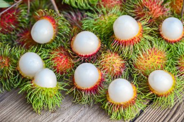 Taze ve olgun rambutan tatlı tropikal meyve yapraklı rambutan, Rambutan meyvesi ahşap arka planda Rambutan ağacı hasadı.