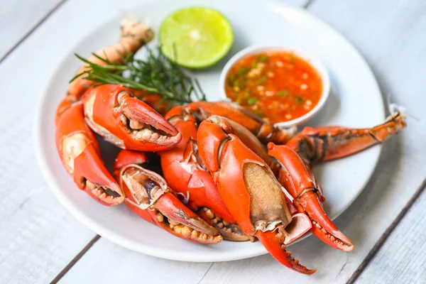 claw crab cooking food seafood plate with chili herbs spices lemon lime salad, fresh crab on white plate seafood sauce, boiled or steamed crab red in the restaurant