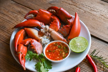 Fresh crab on white plate seafood sauce, boiled or steamed crab red in the restaurant, claw crab cooking food seafood plate with chili herbs spices lemon lime salad