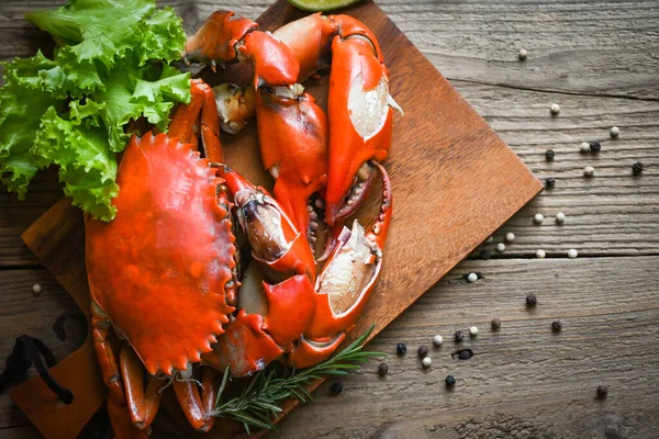 Fresh crab on wooden plate, boiled or steamed crab red in the restaurant, claw crab cooking food seafood plate with chili herbs spices salad