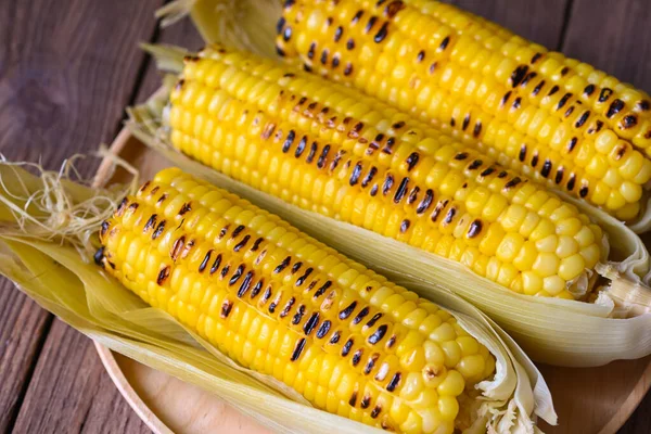 corn food , sweet corn cooked on wooden plate background, ripe corn cobs grilled sweetcorn for food vegan dinner or snack - top view