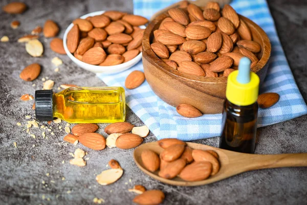 Almond oil and Almonds nuts on bowl dark background, Delicious sweet almonds oil in glass bottle, roasted almond nut for healthy food and snack organic vegetable oils for cooking or spa