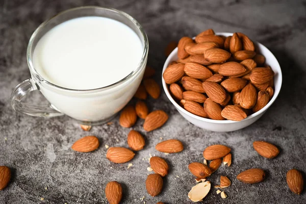 Almond milk and Almond nuts on white bowl with on dark background, Delicious sweet almonds on the table, roasted almond nut for healthy food and snack