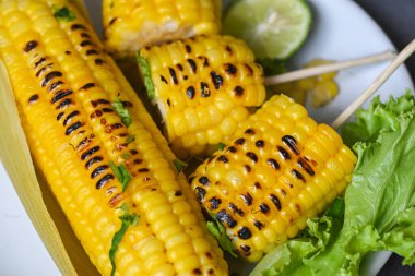 sweet corn food with lime and coriander, ripe corn cobs grilled sweetcorn for food vegan dinner or snack, sweet corn cooked on wooden background