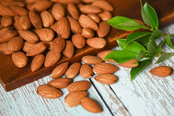 Almonds nuts on wooden background white green leaf , Delicious sweet almonds on the table, roasted almond nut for healthy food and snack